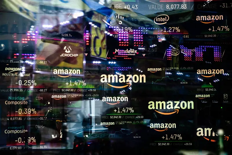 Una pantalla de cotizaciones bursátiles con nombres y precios de varias empresas cotizadas, reflejada en un cristal.
