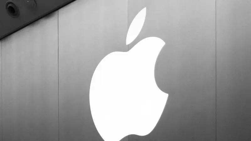 El logo iluminado de Apple en la fachada de una tienda, en blanco y negro.