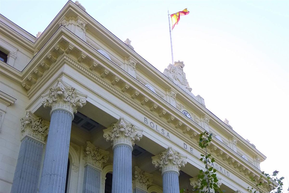 Fachada del Palacio de la Bolsa de Madrid, con sus columnas corintias y la bandera de España.